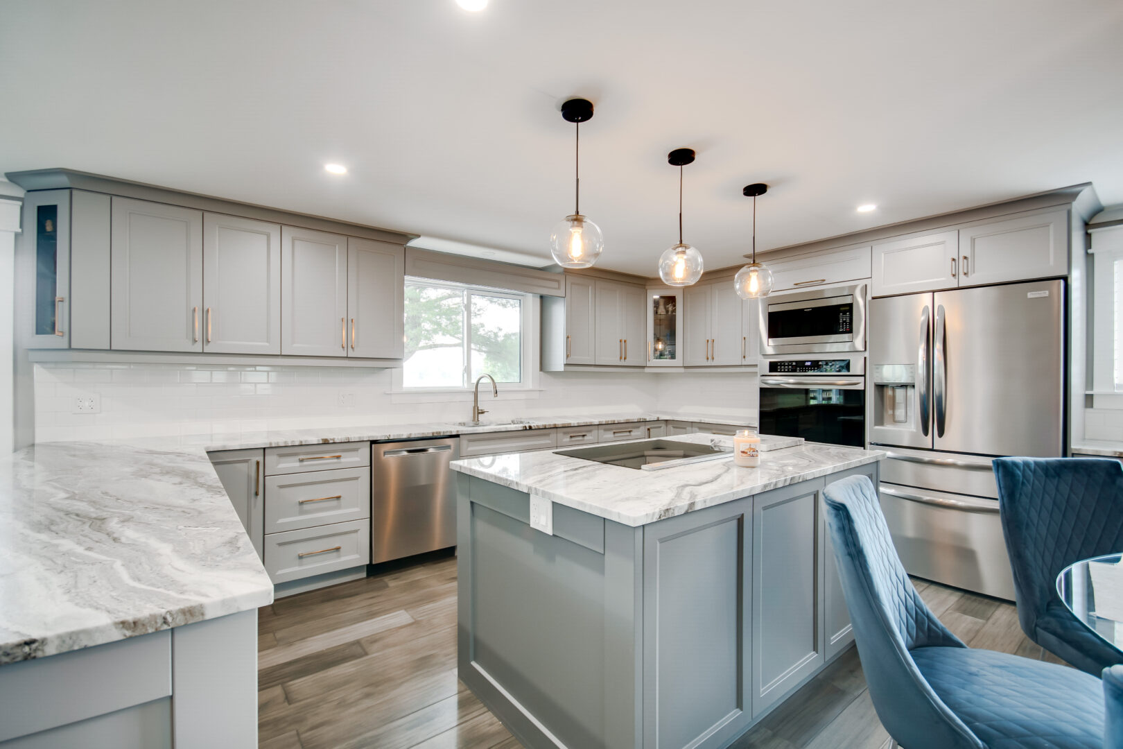 An updated, modern kitchen with new appliances, white cupboards and countertops, and a pale blue island.