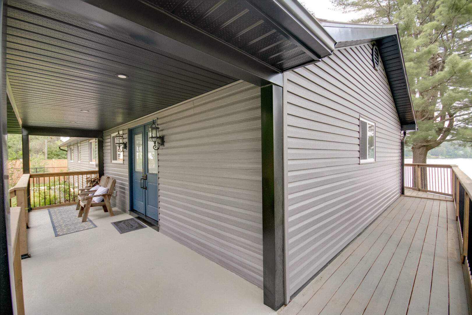 A deck wraps around the side of a bungalow to connect with the front porch.