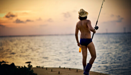 A man fishing in a Speedo and rainboots