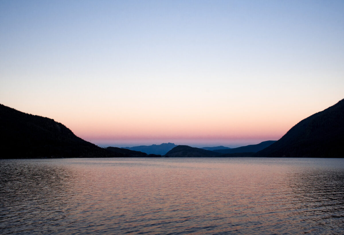Scenic view of Sproat Lake and mountains at sunset