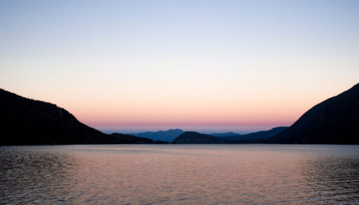 Scenic view of Sproat Lake and mountains at sunset