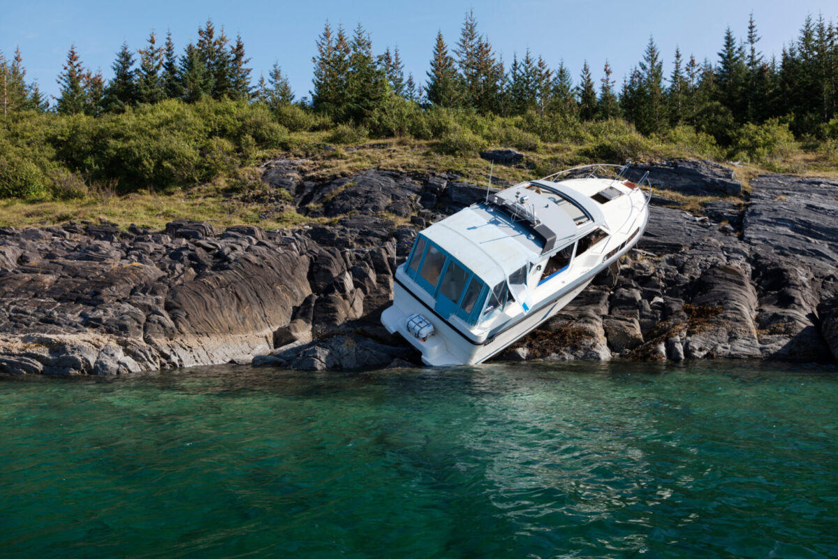 Boat resting awkwardly on a rocky shoreline after an accident