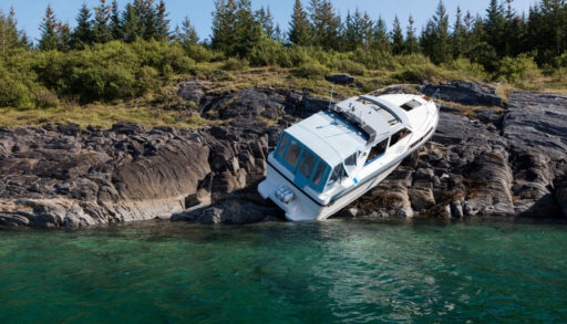 Boat resting awkwardly on a rocky shoreline after an accident