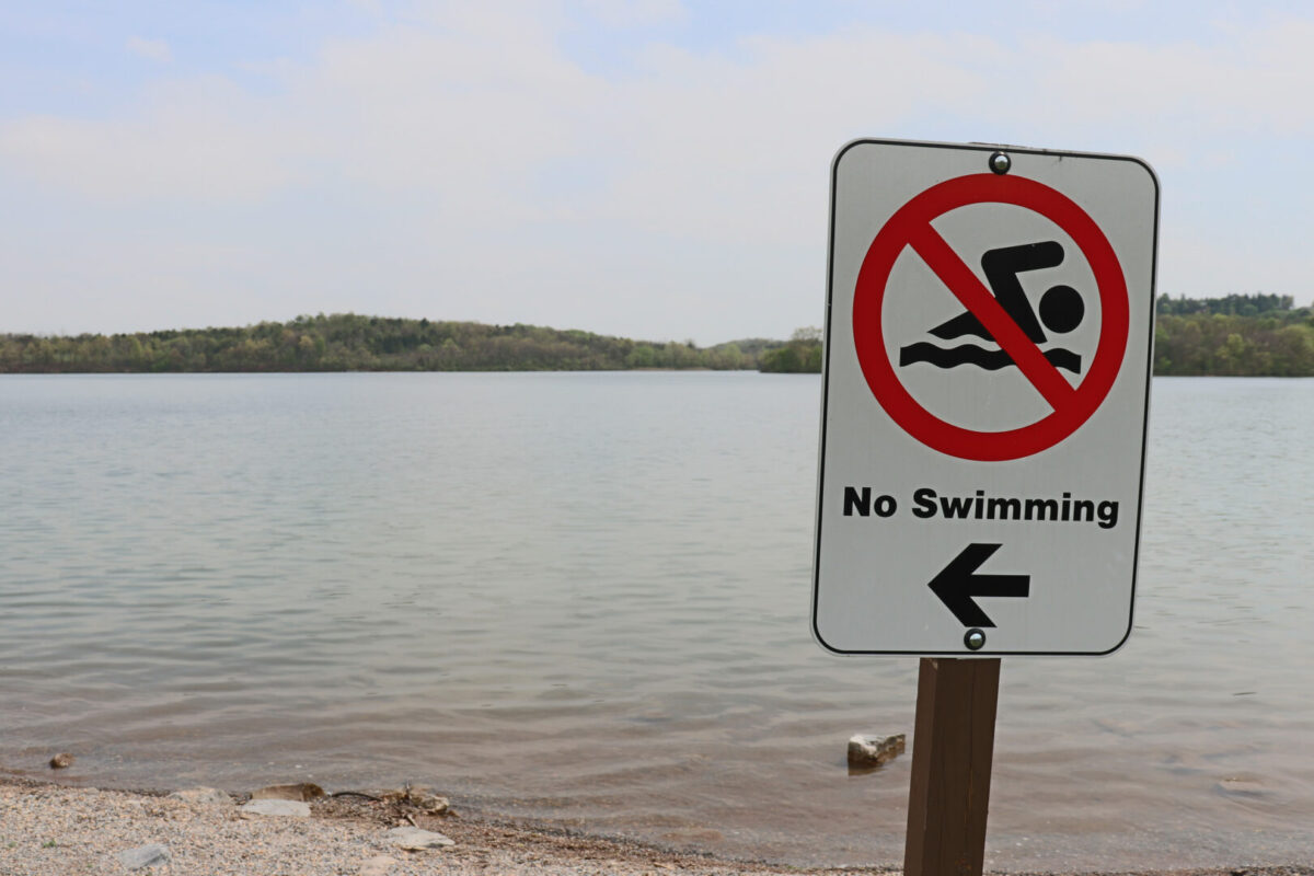 "No swimming" advisory sign posted in font of a beach