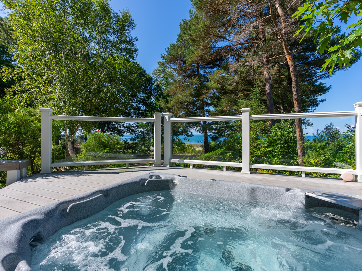 A hot tub on a deck, in front of a glass railing.