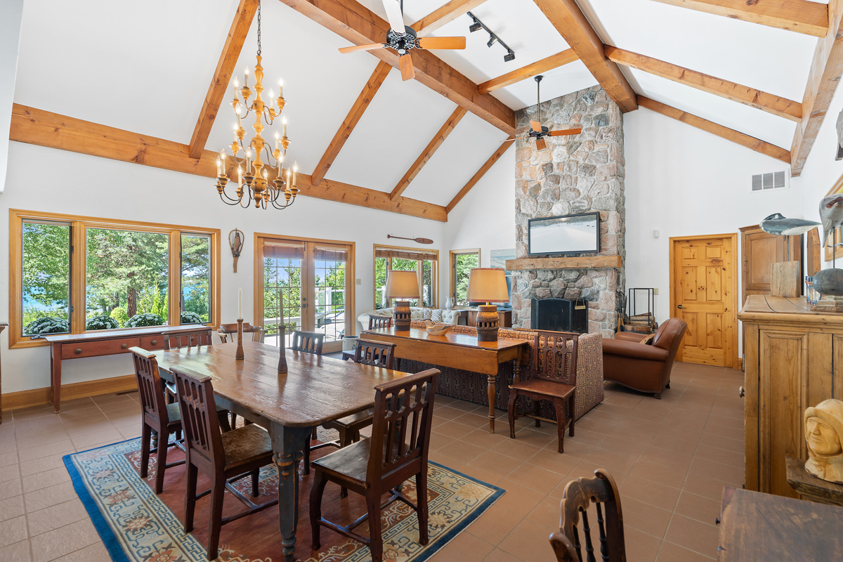 A bright, open-concept main floor space of a luxury cottage, with a floor-to-ceiling fireplace, a living area, and a dining area.