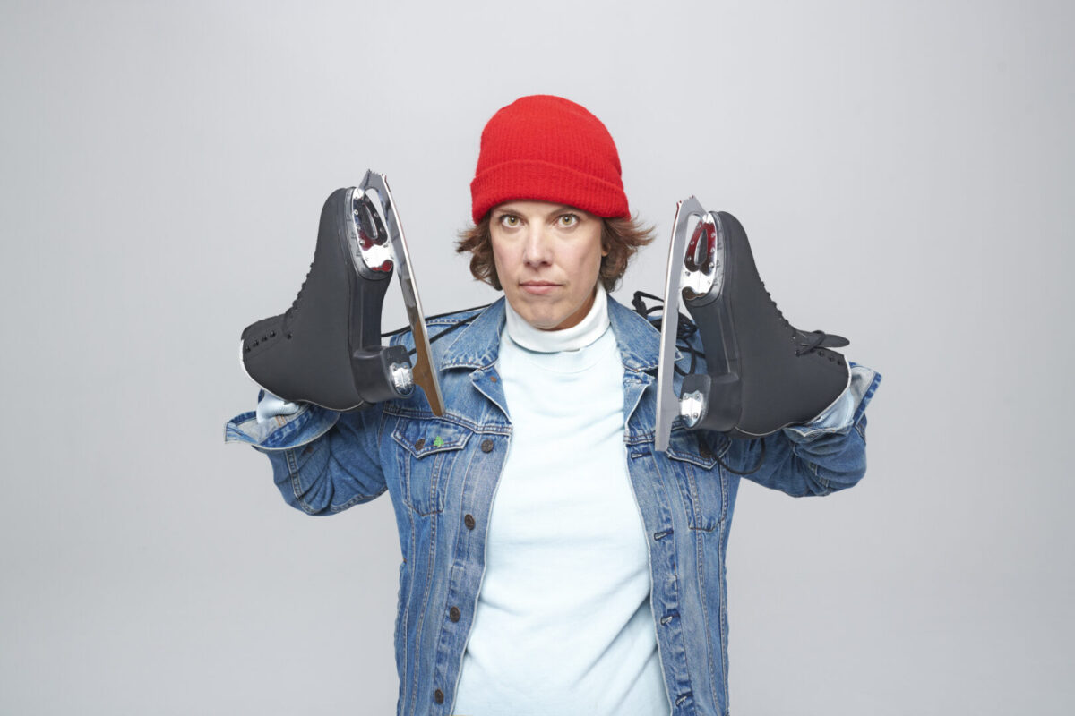 Carolyn Taylor holding up skates and wearing a red hat