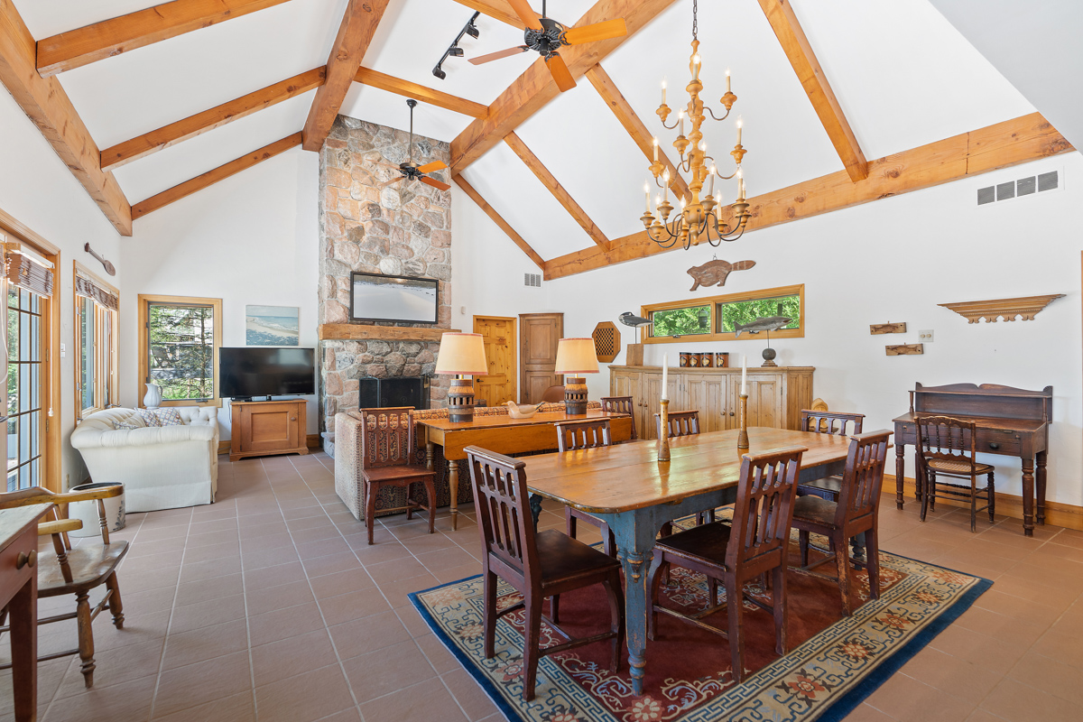 A bright, open-concept main floor space of a luxury cottage, with a floor-to-ceiling fireplace, a living area, and a dining area.