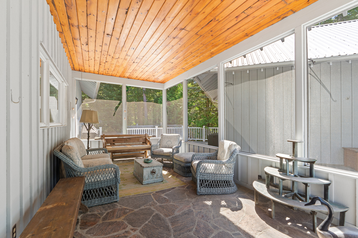 A bright sunroom with lots of seating and a wood-panelled ceiling.