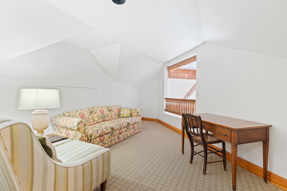 A small living area in front of a railing looking out over the lower level of a home.