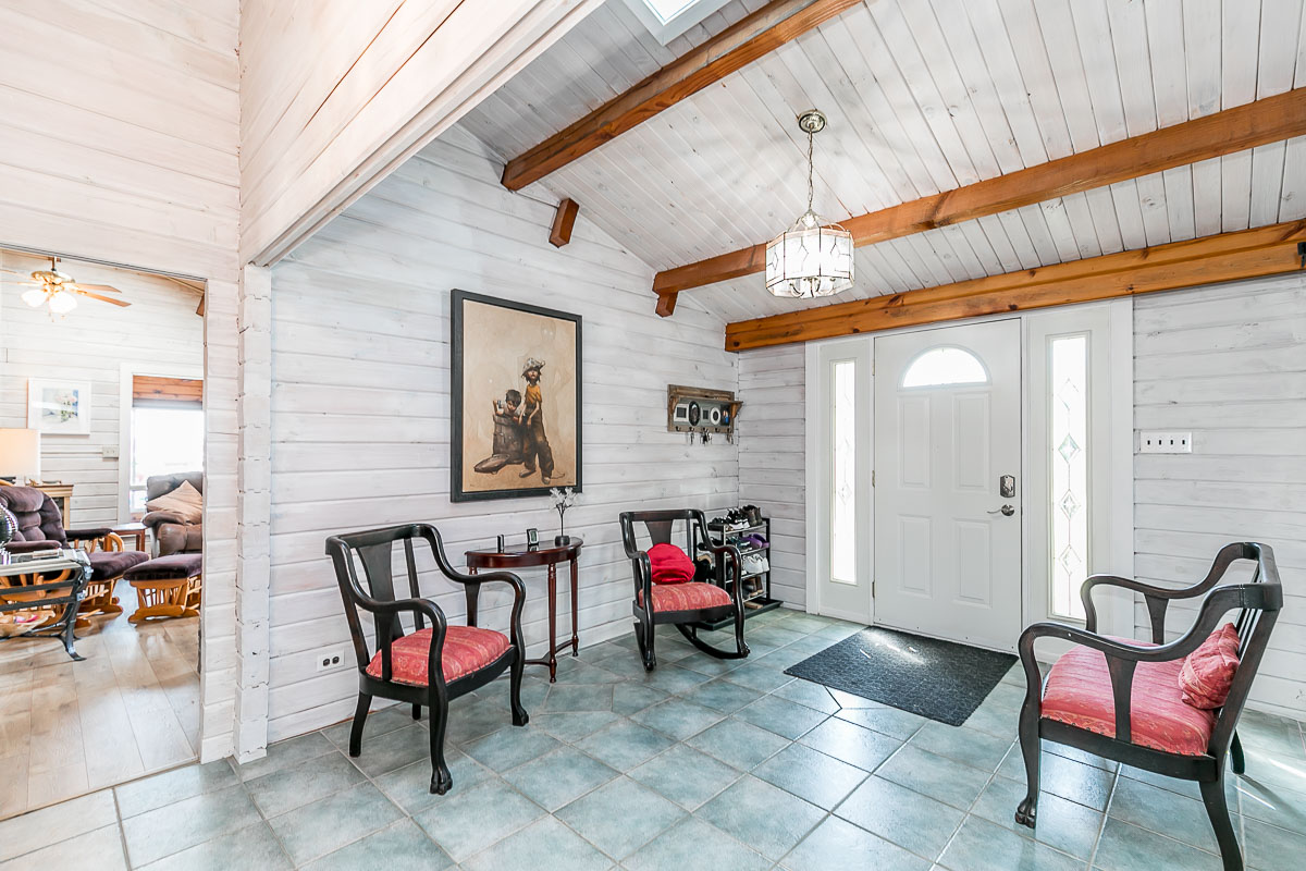Inside a bright entrance with tile floors and painted white wood-panelled walls and ceilings.
