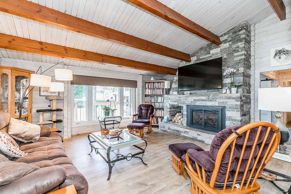 A bright living space with a couch, two rocking chairs, a television, and a fireplace.