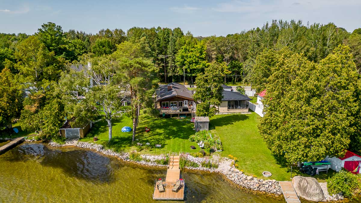 A cottage property sits on the edge of a lake. A big dock extends into the water.