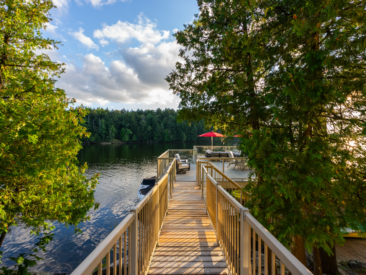 A walkway stretches from a cottage deck to a waterfront rooftop deck.