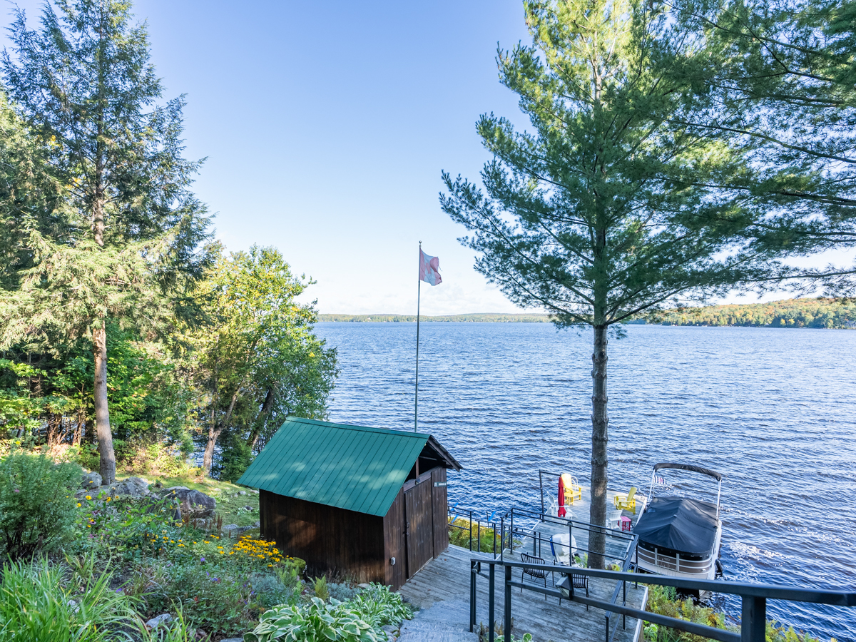 View from the steps, looking down toward the waterfront, which has a small boathouse and a dock.