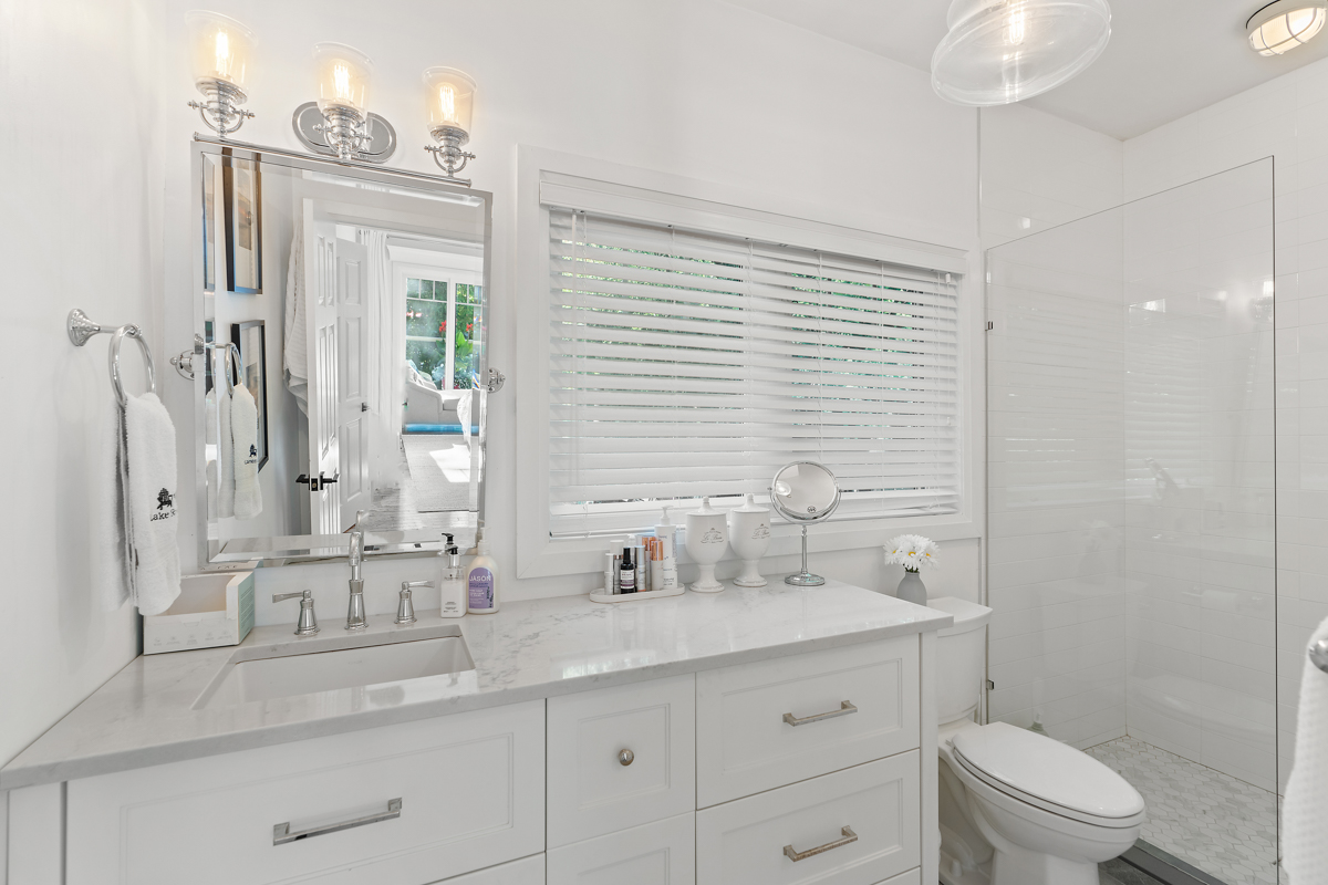 A white ensuite bathroom with a toilet, a sink, and a walk-in shower.