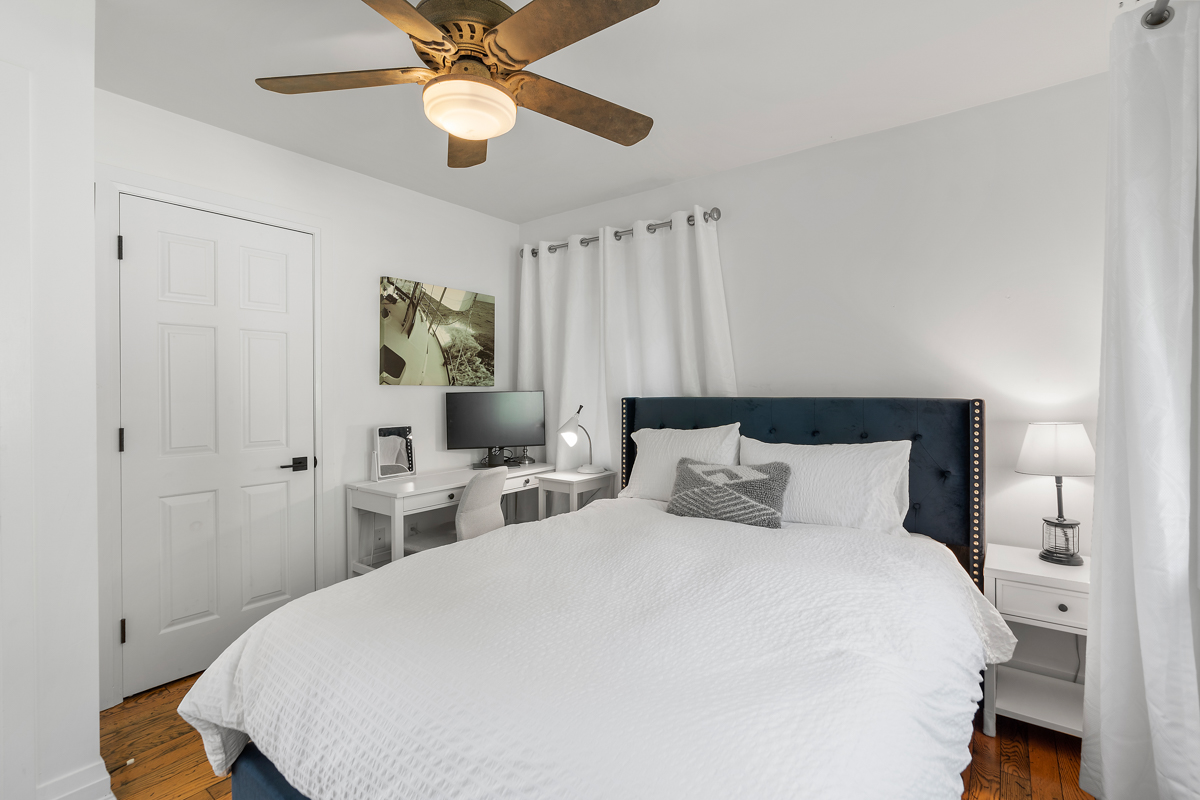A bright bedroom with a big bed and a small desk.