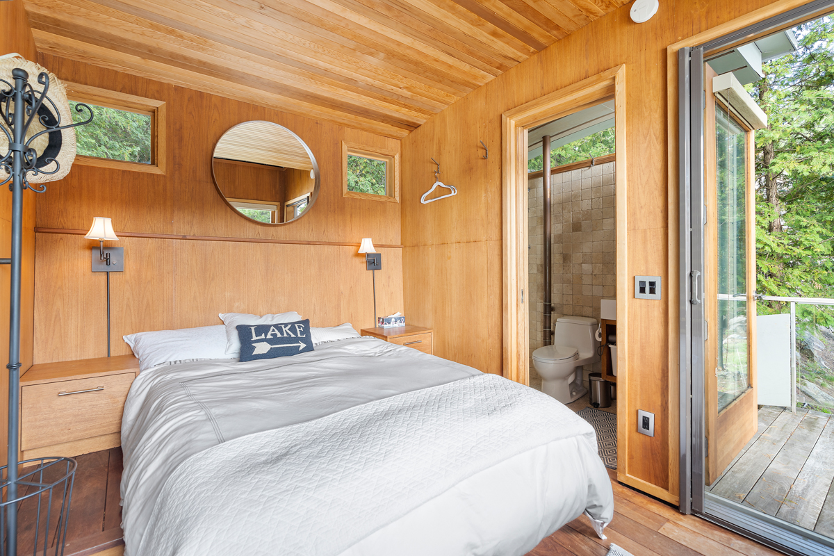 A large bed in a mall bunkie with wood-panelled walls.
