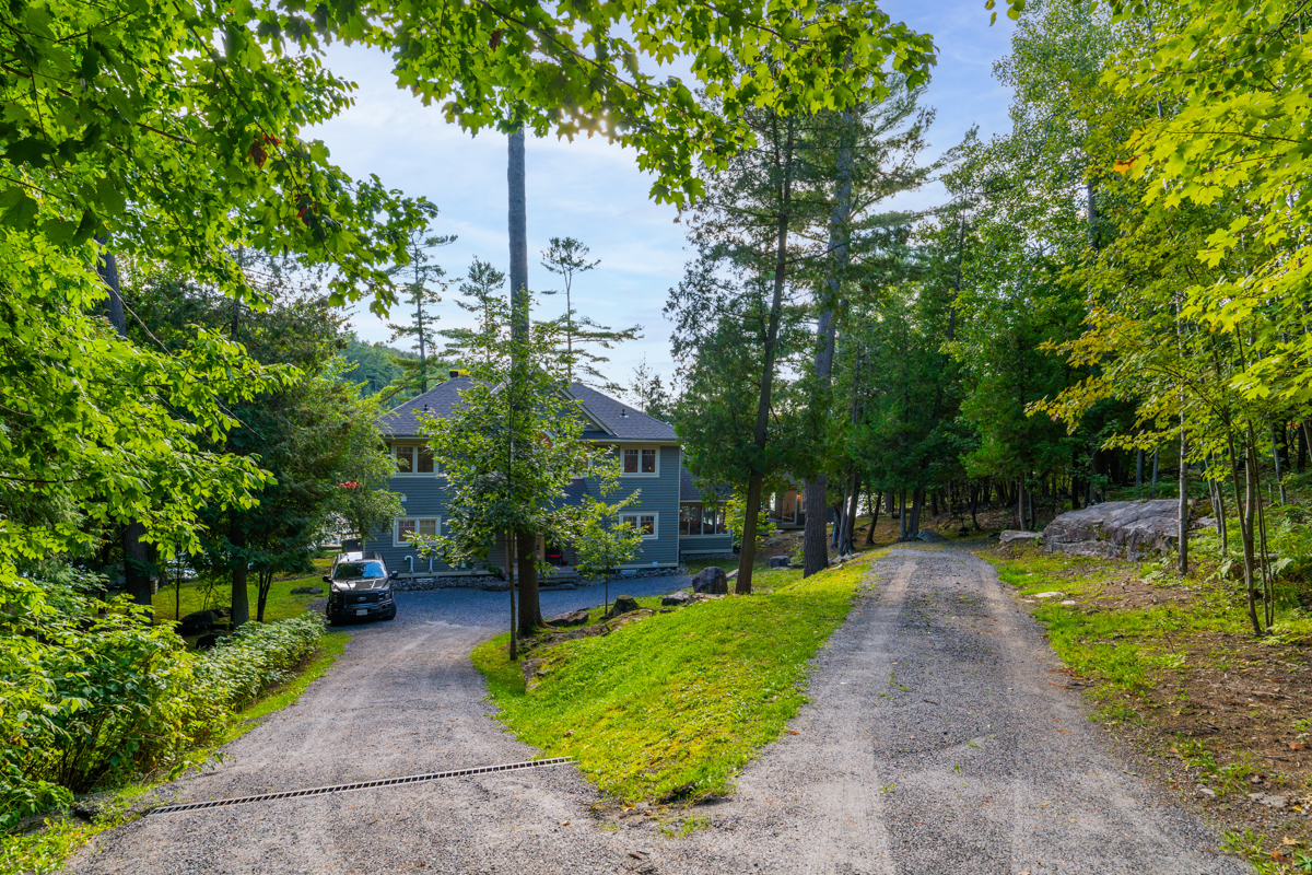 A dirt and gravel driveway leads to a large cottage.