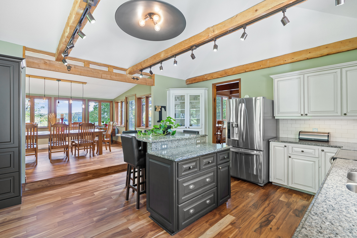 A big, updated kitchen with hardwood floors and light green walls.