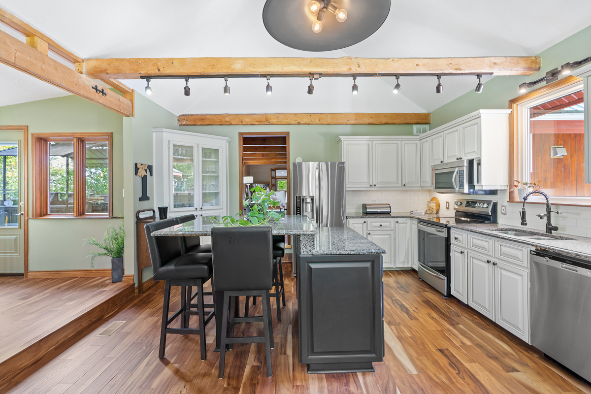 A big, updated kitchen with hardwood floors and light green walls.