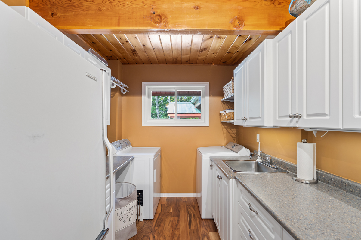 A small area with a washing machine, a dryer, extra cabinets, and a fridge.