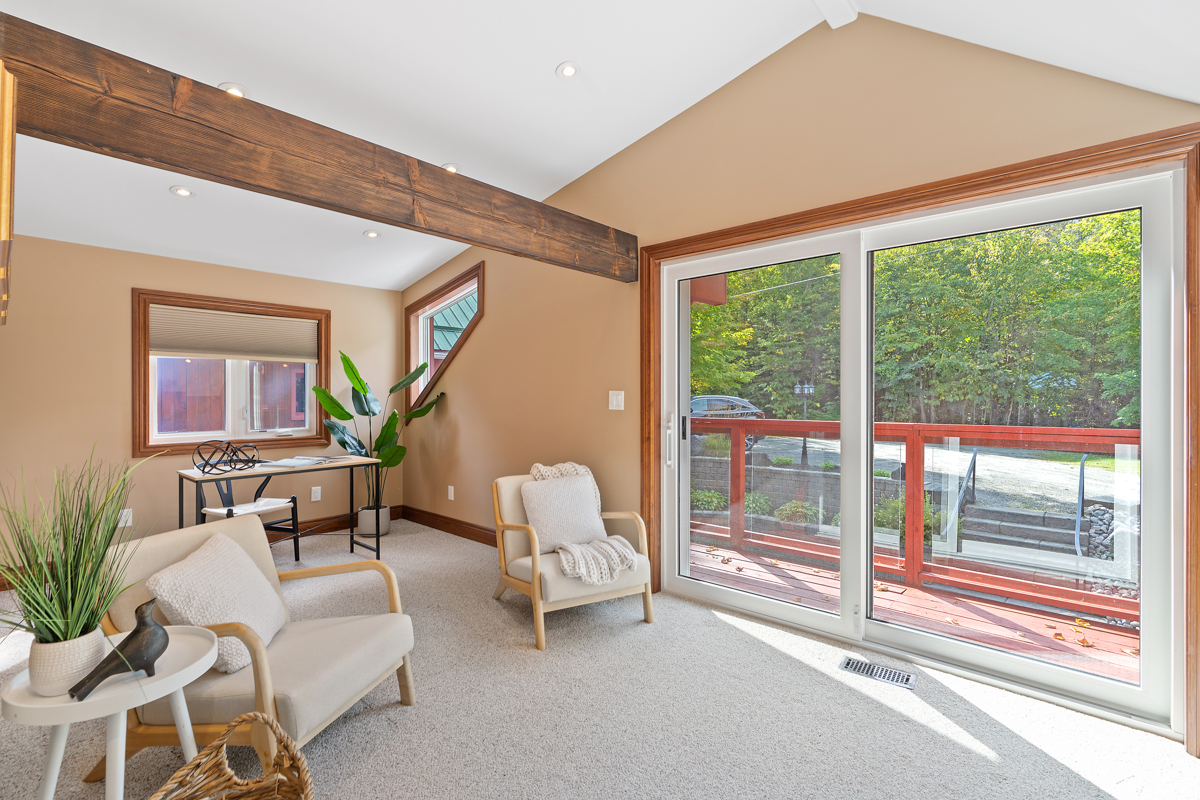 A large sitting area with two chairs, a small desk, and double doors that lead out to a balcony.