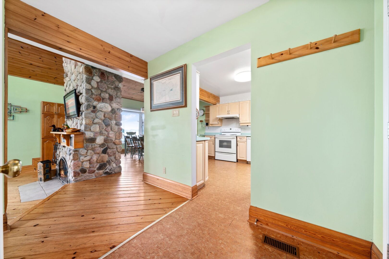 Entrance of a cottage with light green walls and a doorway that leads to a kitchen area.