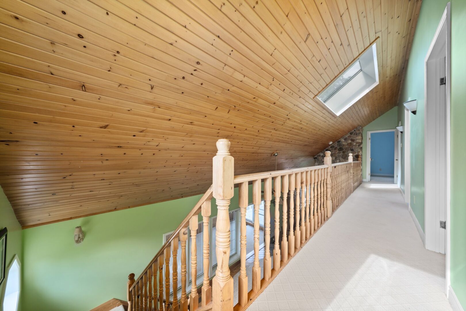 An upper-level hallway with an open railing that looks out to the lower level below.
