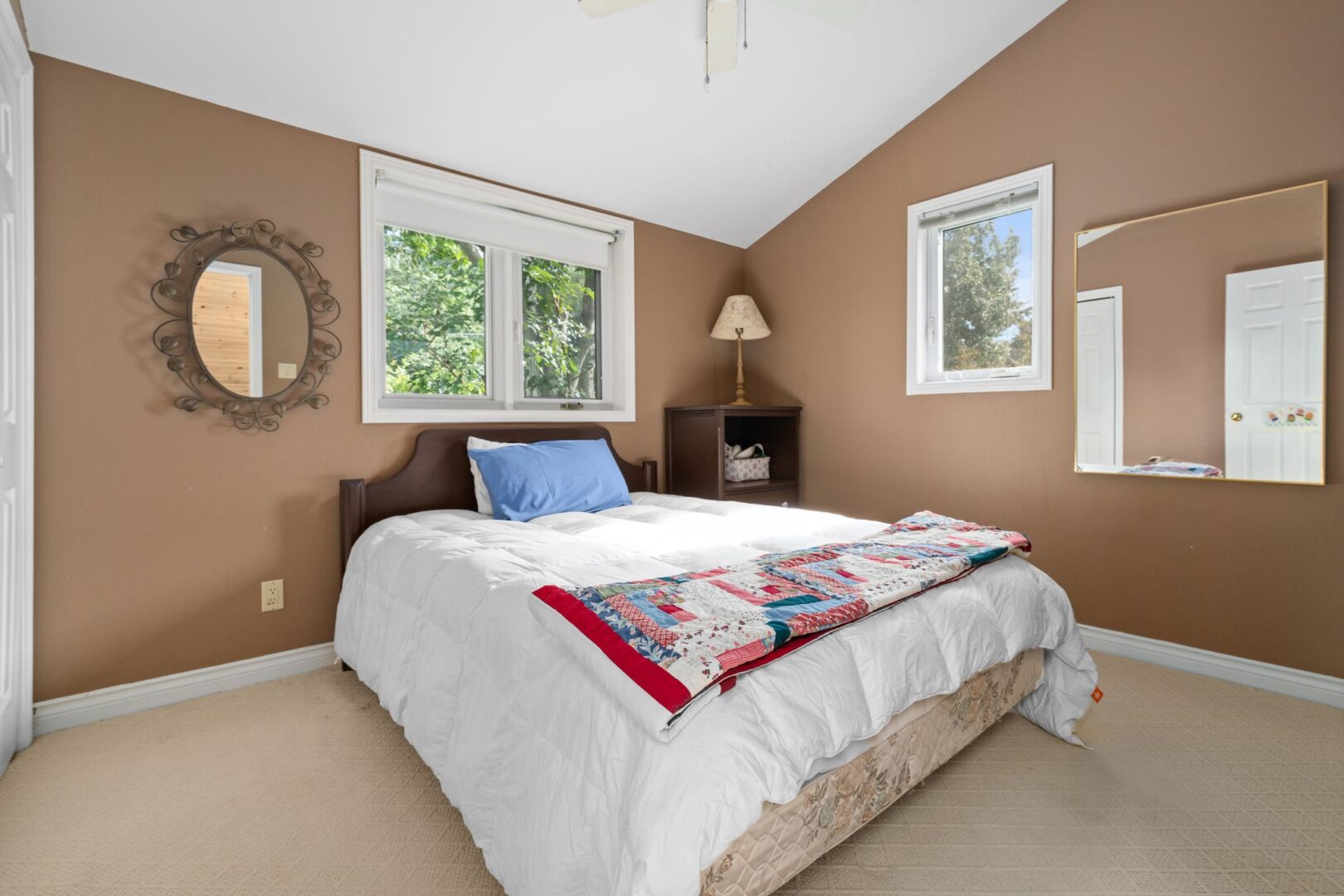 A big bedroom with light brown walls, a sloping ceiling, and a big bed.