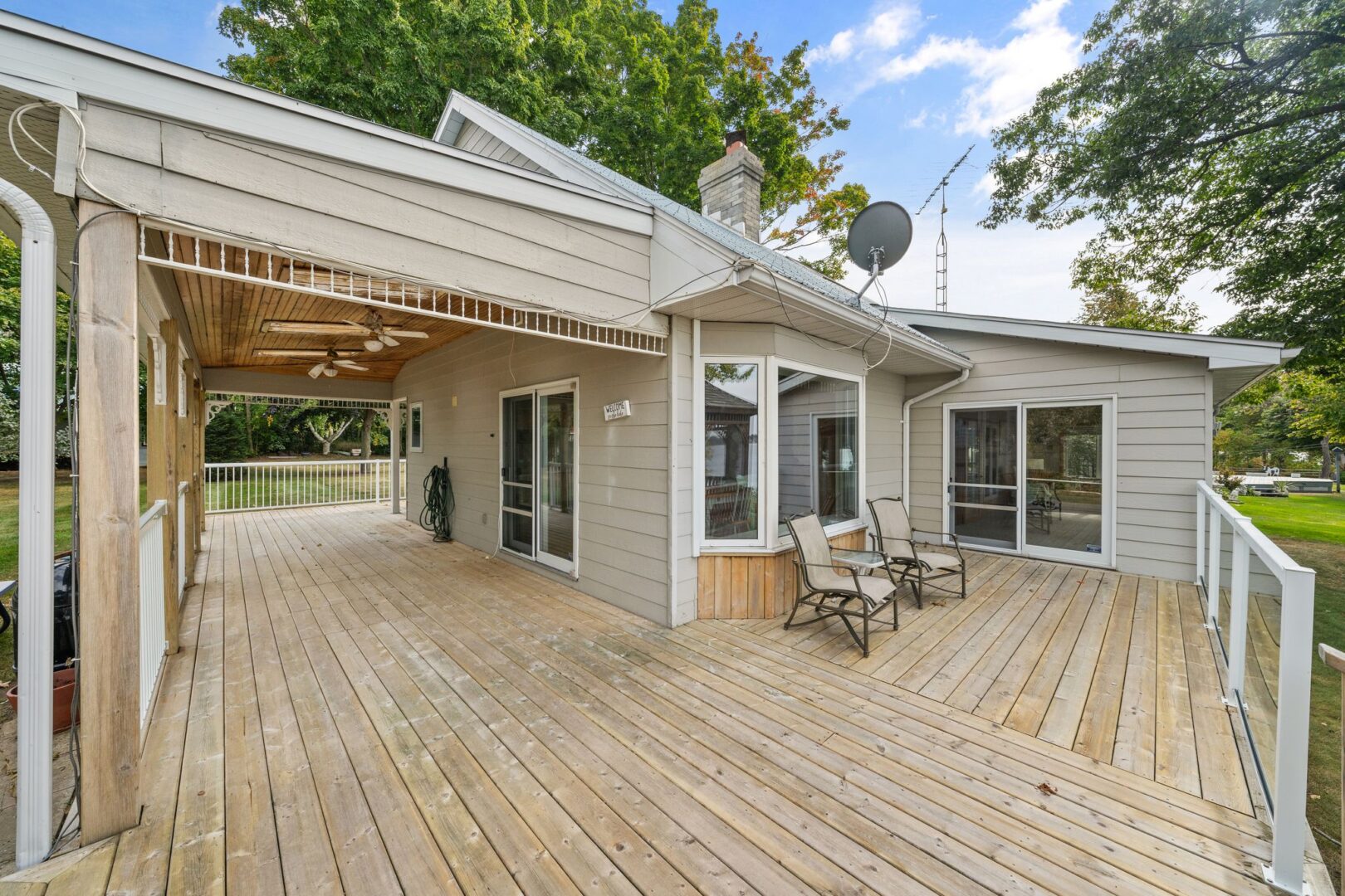 A large back deck extending off the wrap-around porch on a cottage.