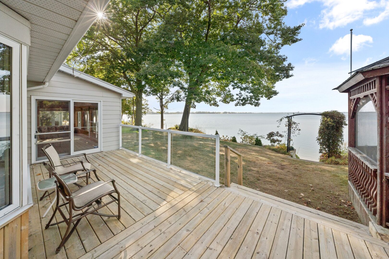 A large back deck of a cottage, looking out over the lake.