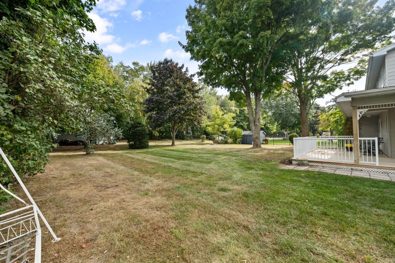 A large, grassy outdoor space beside a cottage with a wrap-around porch.