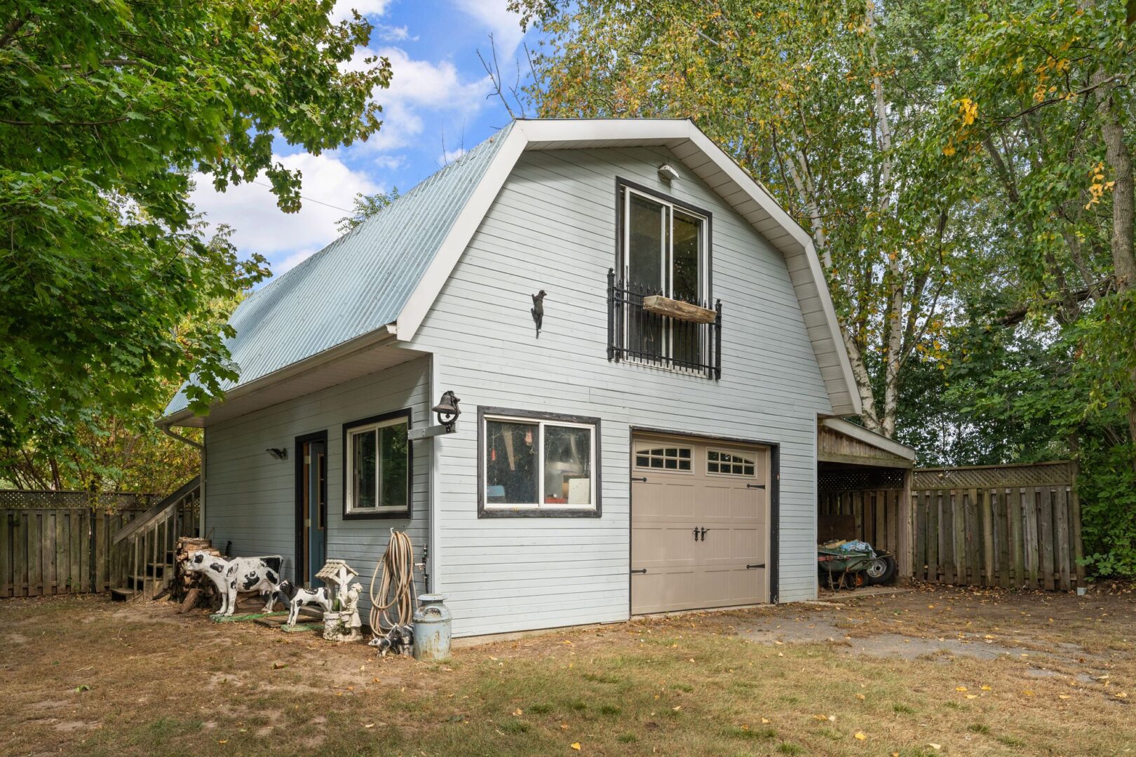 A detached two-story garage with a garage door, a separate entrance, and stairs up to a loft space.