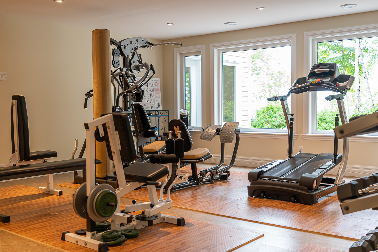 A bright room with lots of home gym equipment and lots of windows.