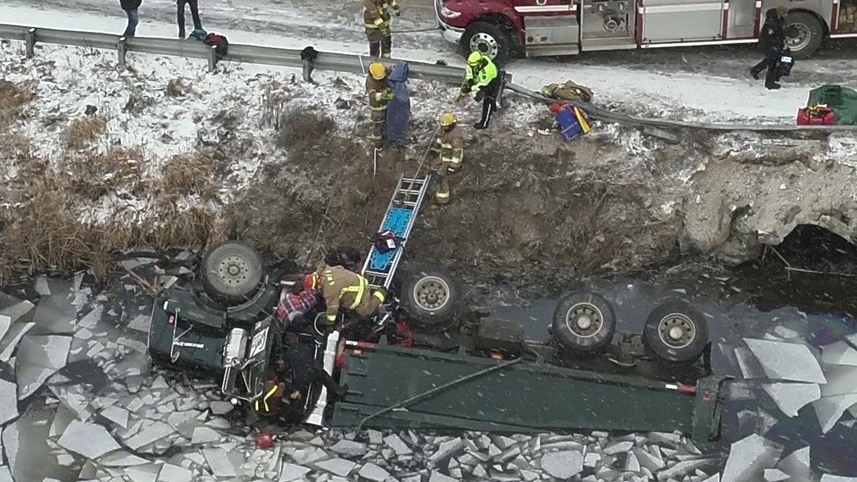 Emergency personnel help release the trapped truck driver