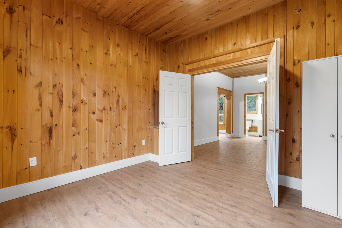 A big, empty bedroom with wood panelling on the walls and ceiling.