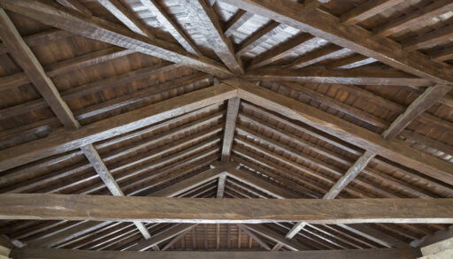 A wood ceiling with exposed rafters and joists