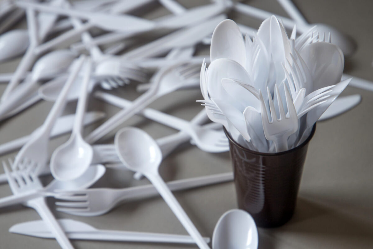 white plastic forks in a cup and spread out on a table