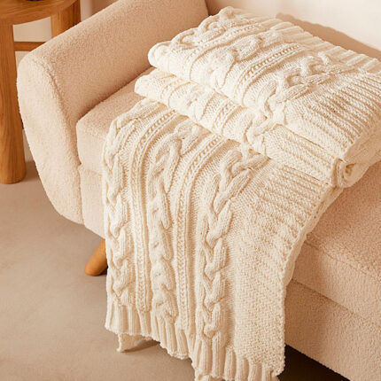 a white chenille blanket draped on a white couch