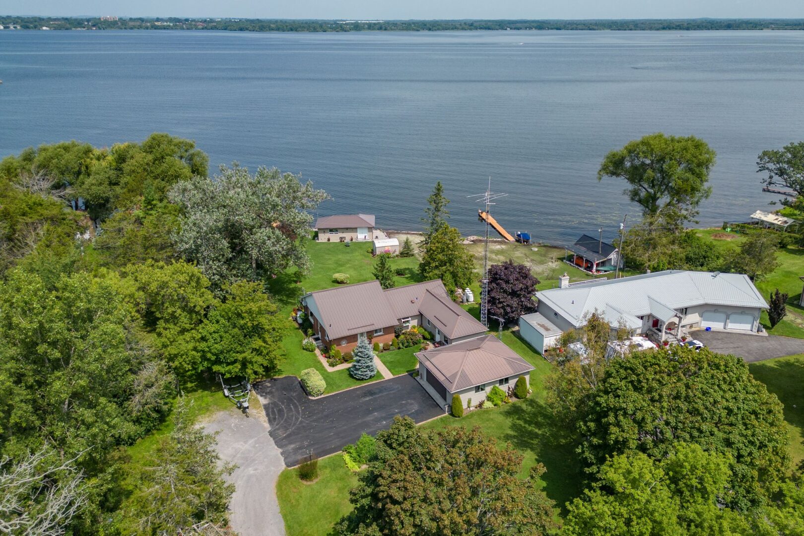 Overhead view of a waterfront bungalow with a big driveway and a detached garage.