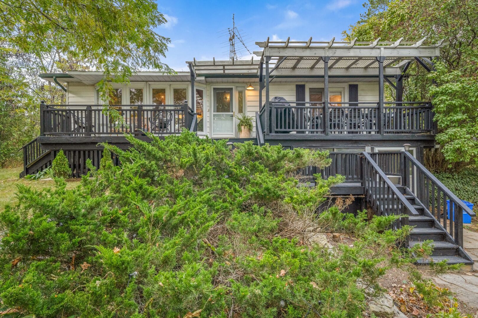 The front of a raised bungalow with a big front porch that's painted dark grey.