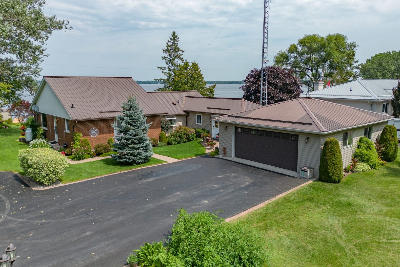 A big paved driveway extends from a detached garage beside a bungalow.