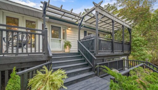 Stairs lead up to the front porch of a raised bungalow. The stairs and porch are painted a dark grey colour.