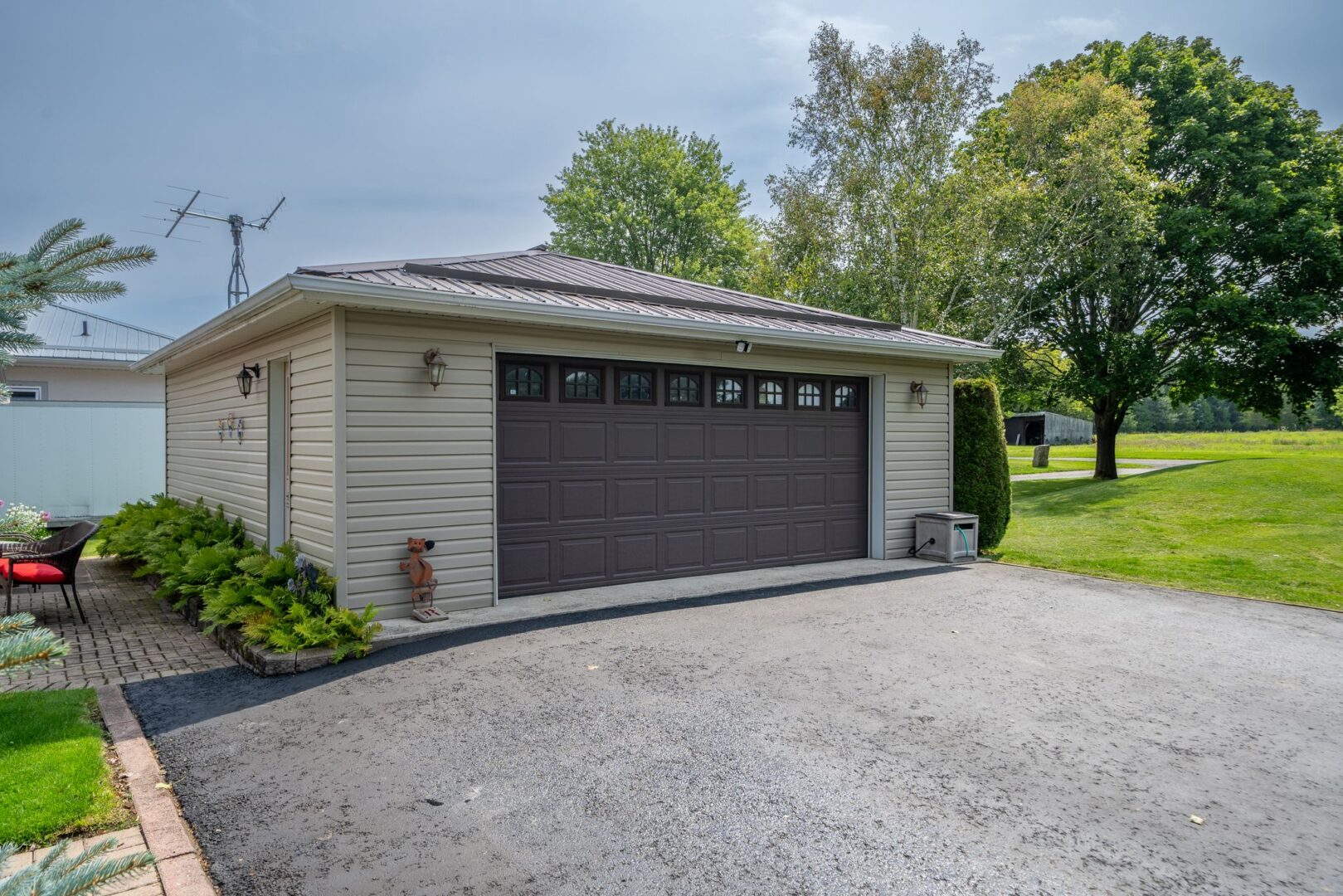 A large detached garage with a dark brown garage door and a paved driveway.