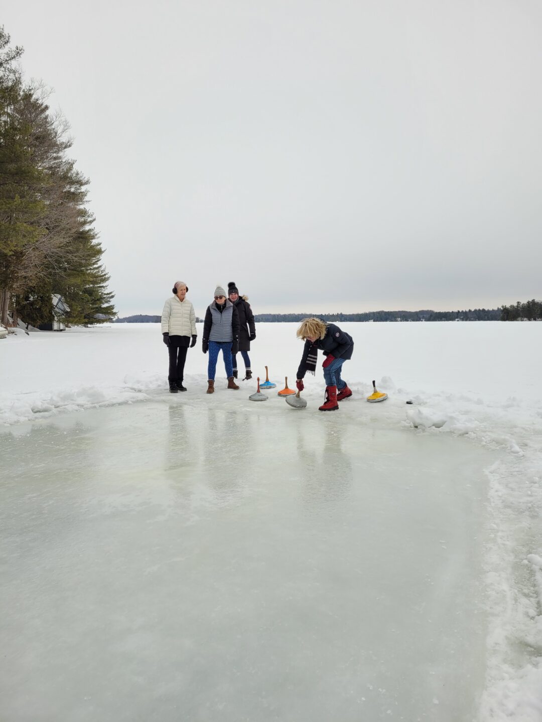 a group of adults playing ice stock sport outdoors on a frozen lake