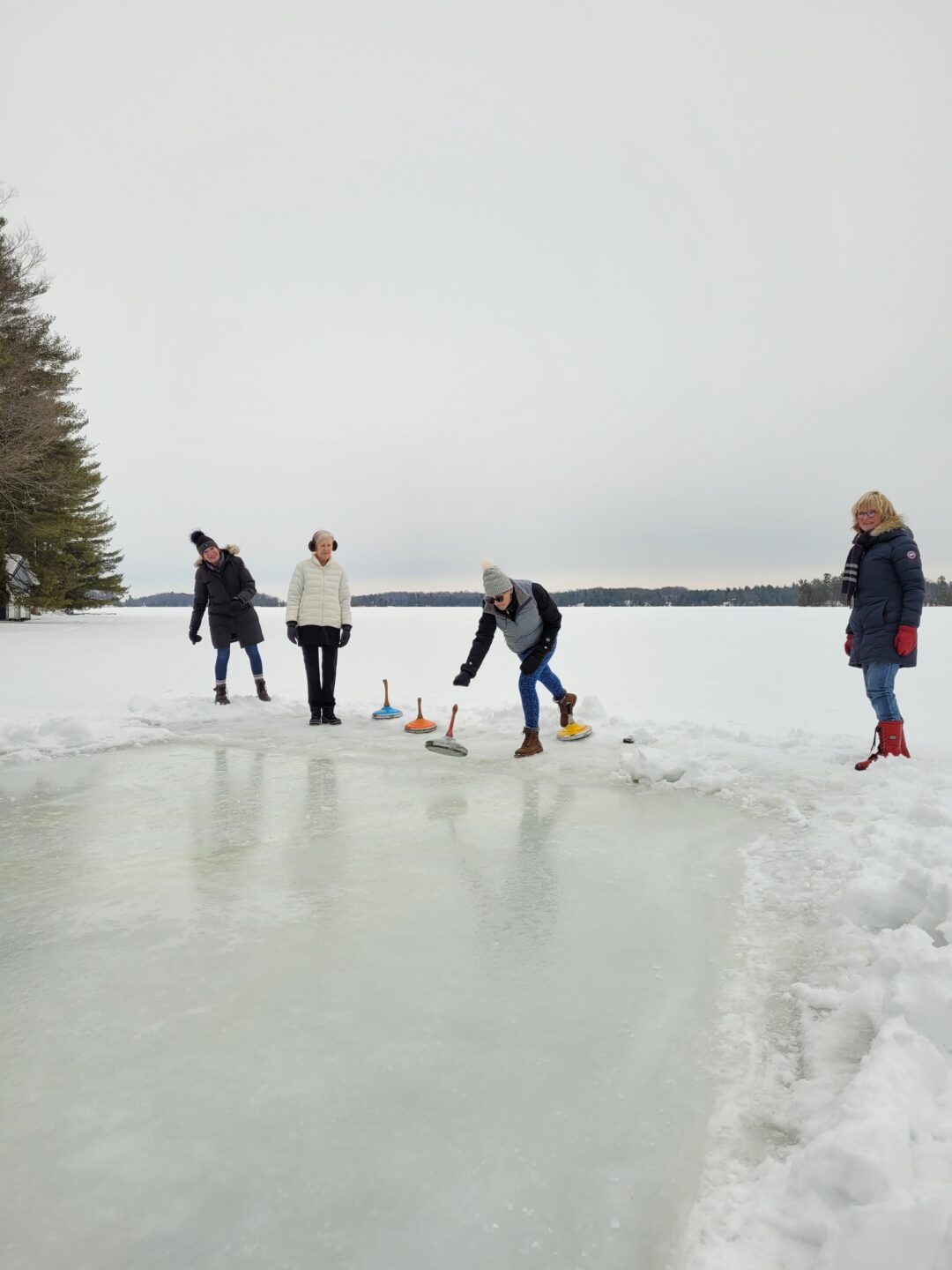 a group of adults playing ice stock sport outdoors on a frozen lake