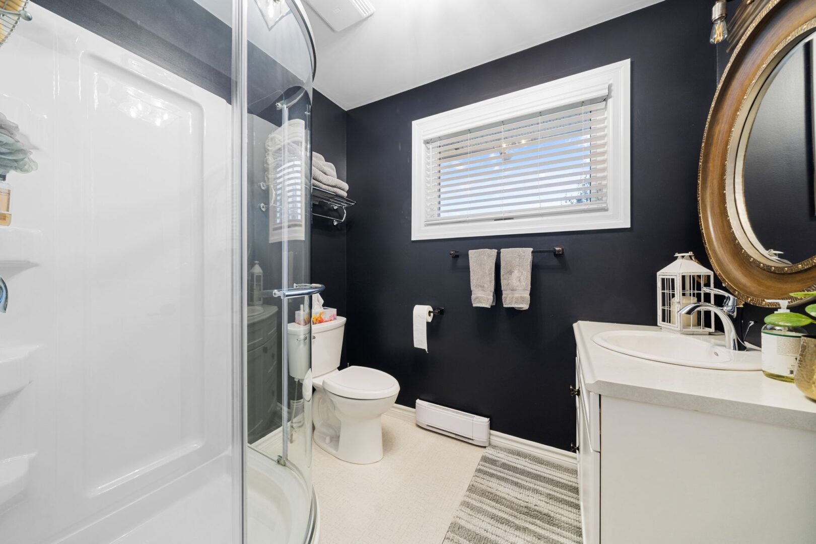 A bathroom with black walls, a toilet, a sink, and a walk-in shower.