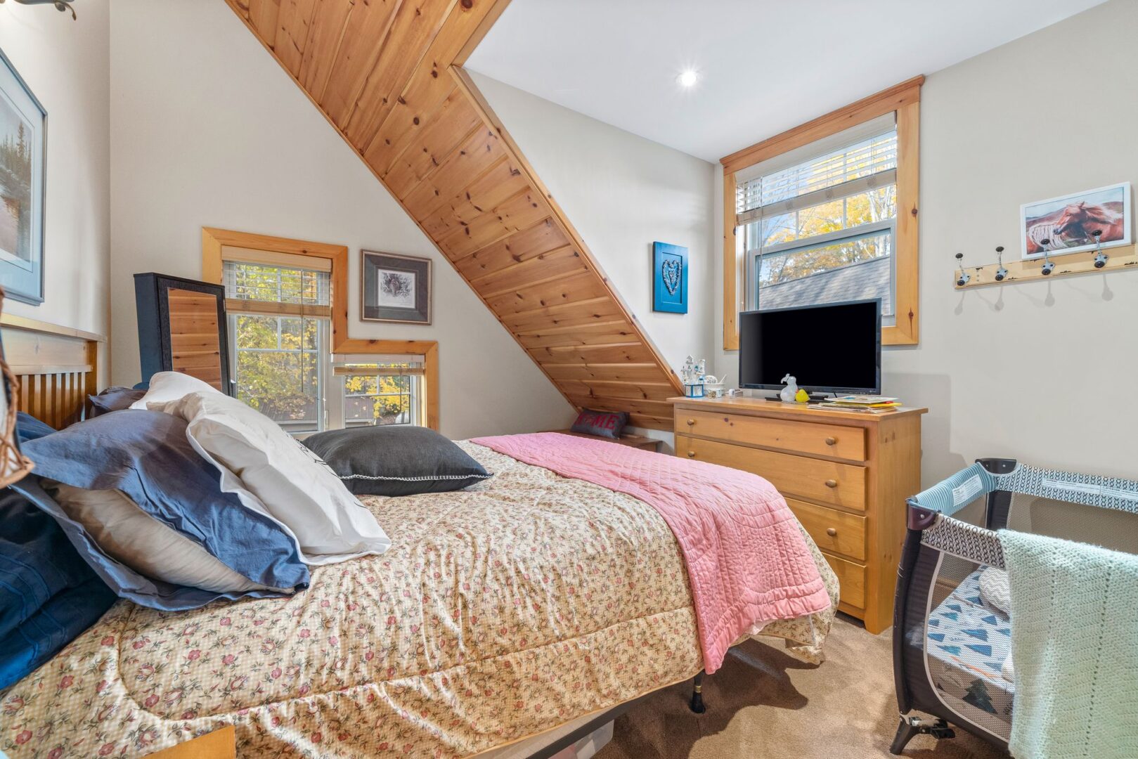 A small but bright bedroom with a medium-sized bed and a sloping ceiling.