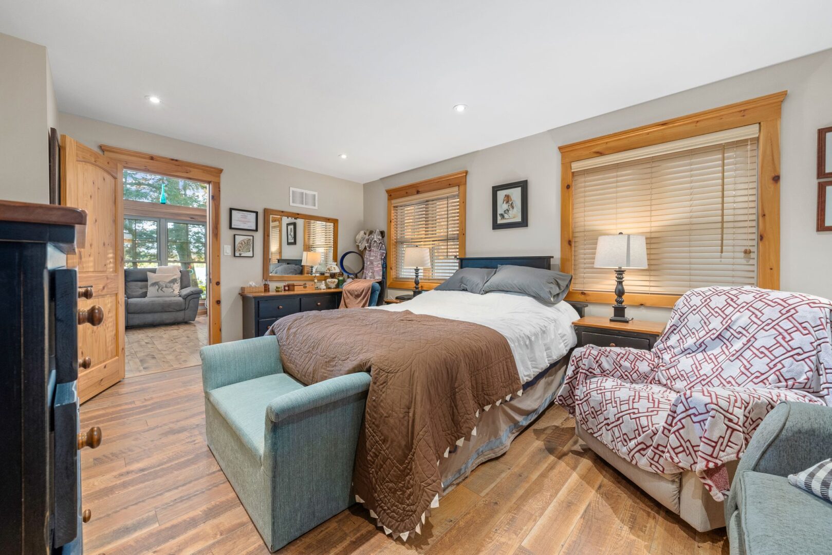 A big bedroom with hardwood floors and a large bed. The open doorway leads out to the living area.